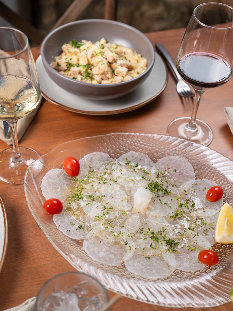 Fish carpaccio with lemon and herbs, served with white and red wine.