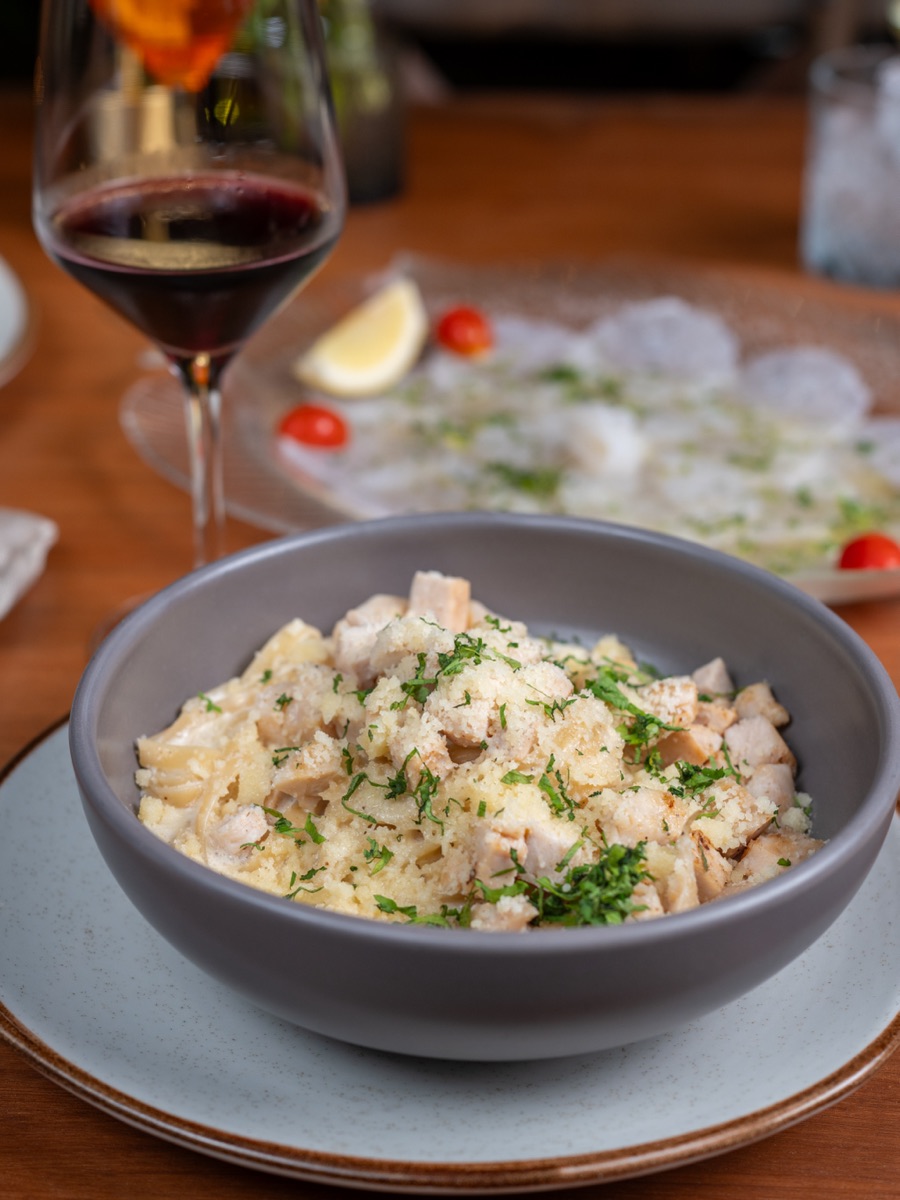 Creamy chicken pasta with parmesan, next to a glass of red wine.