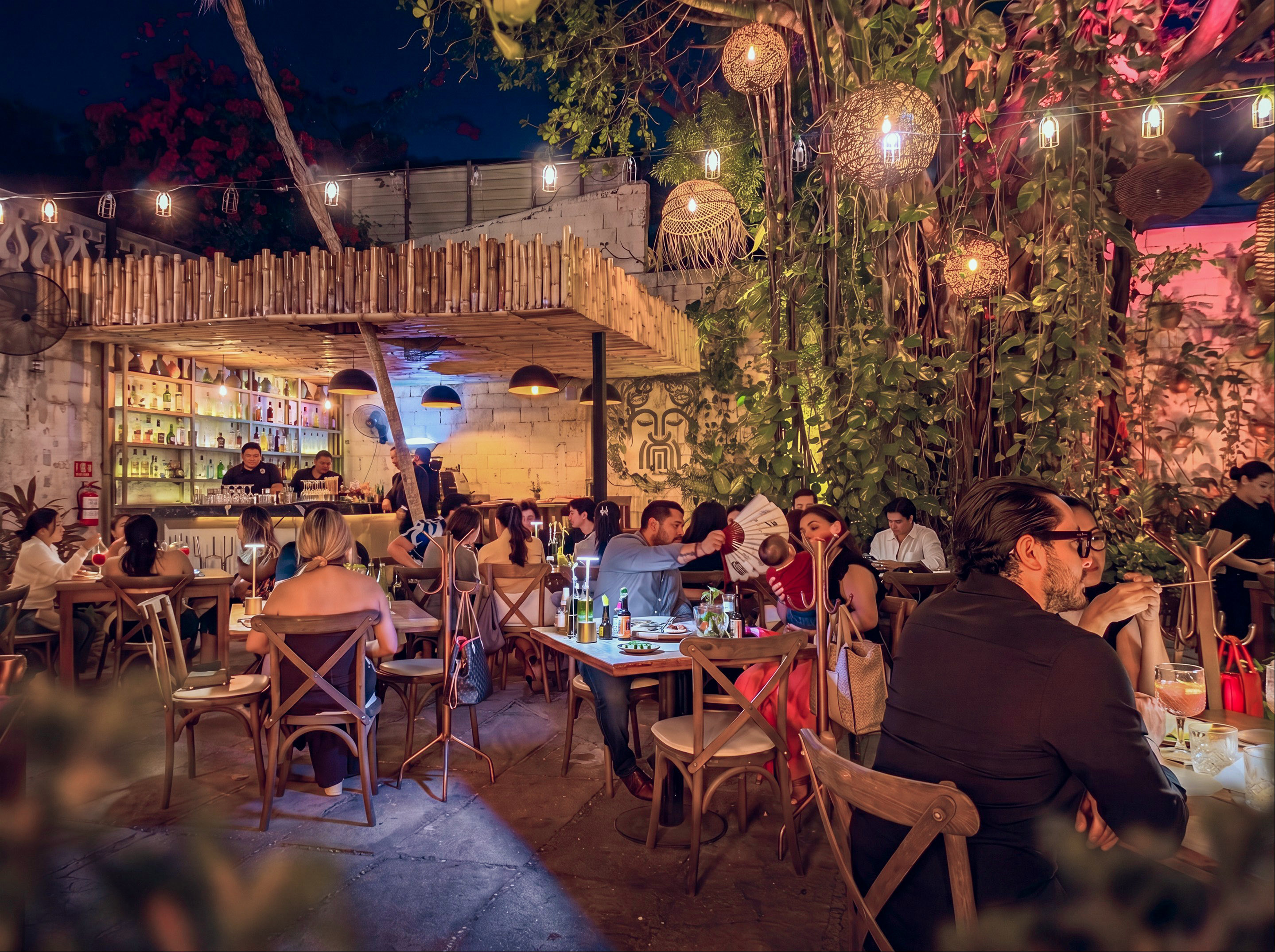 Mar Di Vino patio at night — tables under the canopy, warm lights and the bamboo bar in the back.