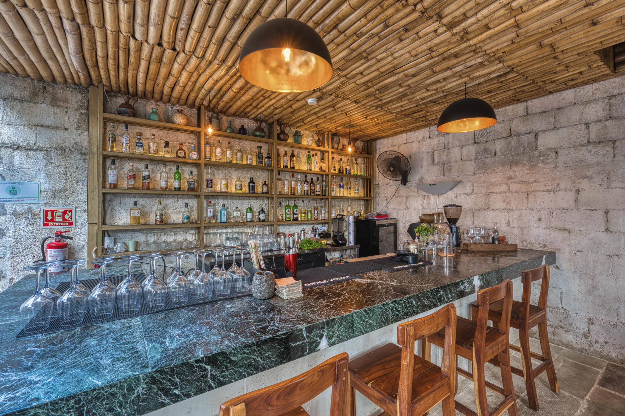 Mar Di Vino's green marble bar under the bamboo ceiling, bottles lined up on wooden shelves.