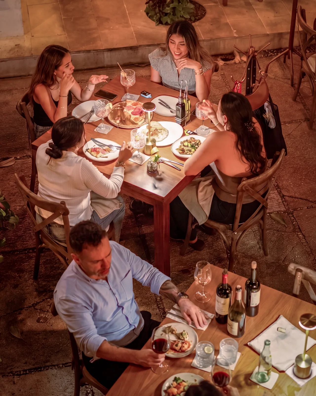 Group of friends sharing plates and wine on Mar Di Vino's terrace at night
