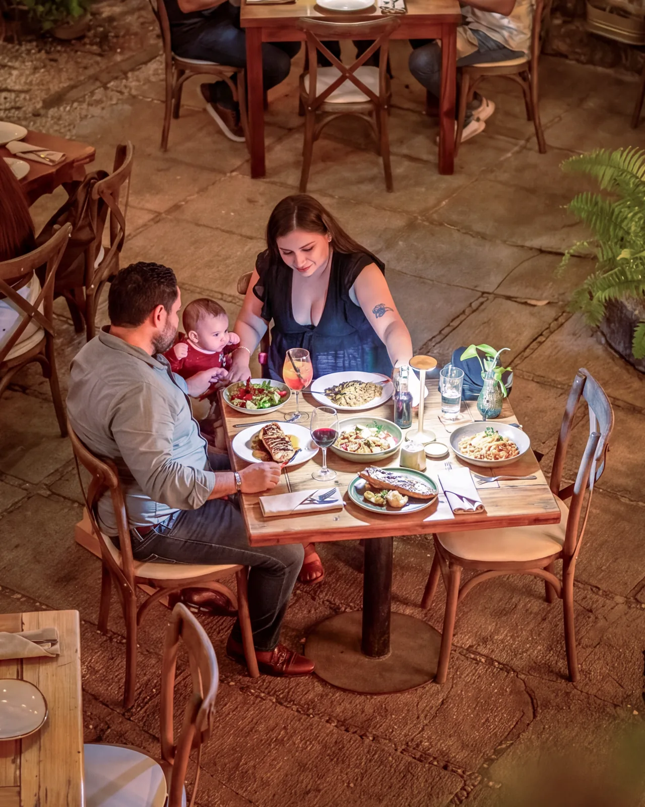 Family having dinner at a wooden table on Mar Di Vino's terrace, seen from above