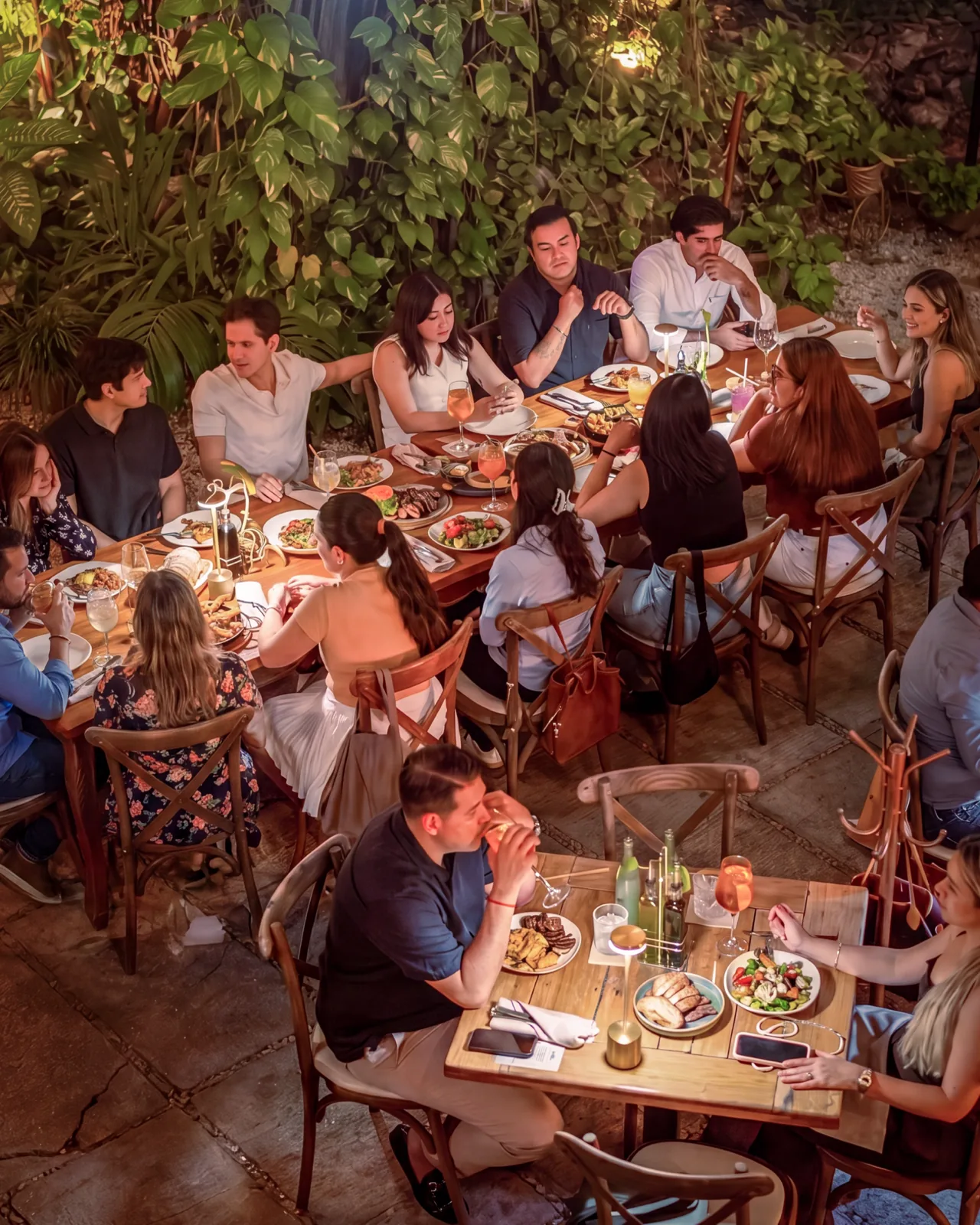 Tables full of diners on Mar Di Vino's garden terrace, surrounded by greenery